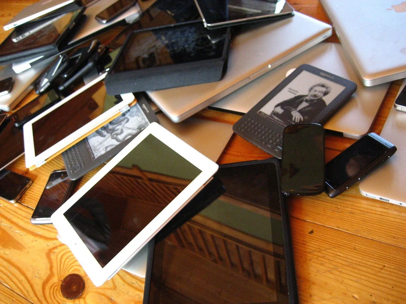Une table couverte de téléphones et tablettes usagés.