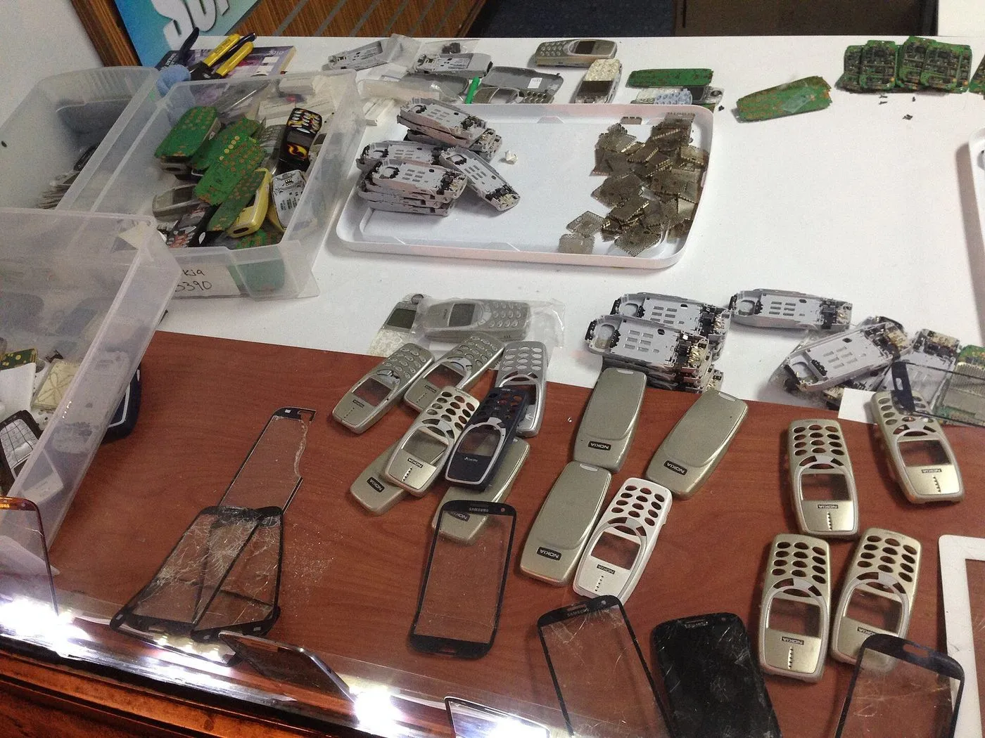 Des téléphones démontés et triés sur une table d'atelier de recyclage.